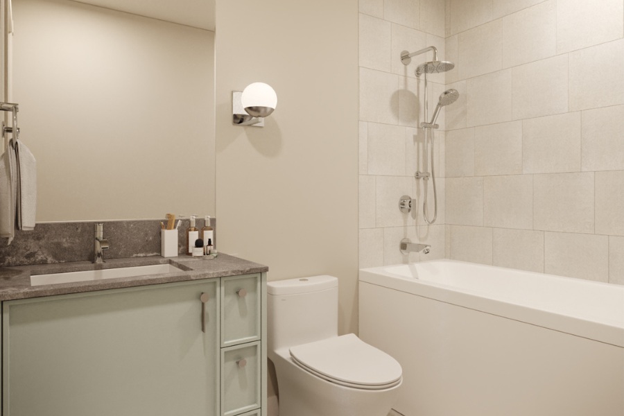 A rendering of a residential home bathroom at Tresah East with light green cabinetry, a white toilet, and a tiled shower with a tub inset.