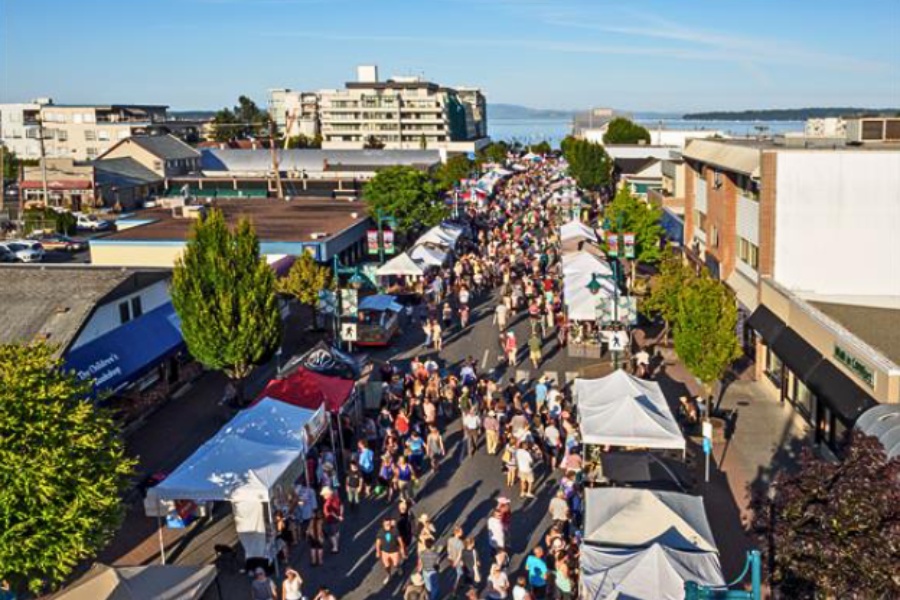 An aerial view of a street market in Sidney, BC with lots of people and tents with vendors.