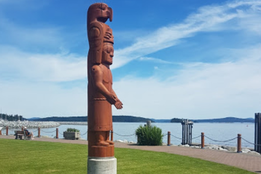 A totem pole in Tulista Park with the ocean behind.